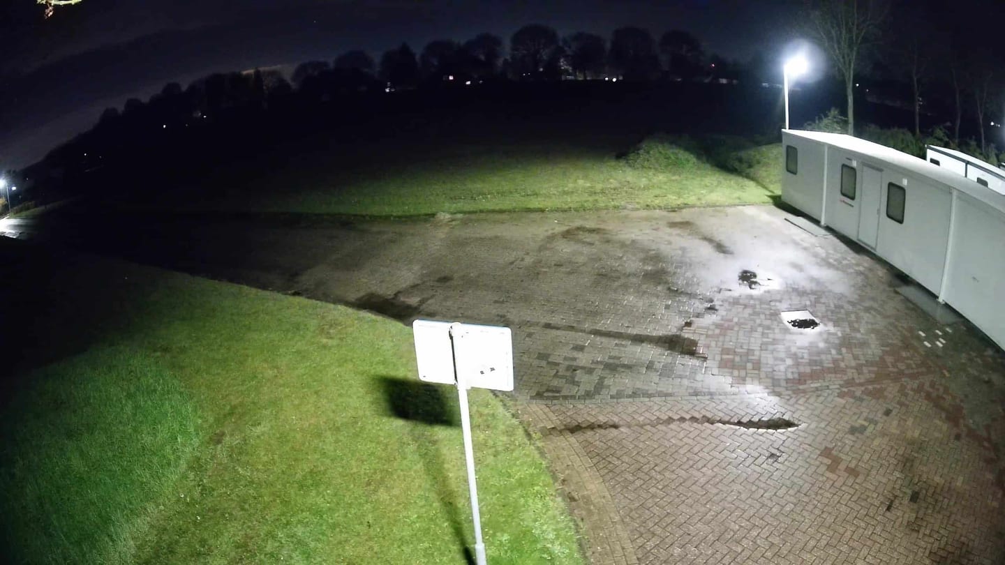 50+ Bewakingscamera Tips en Adviezen: camerabeeld in het donker van een grasveld en een verhard terrein met een lantaarnpaal