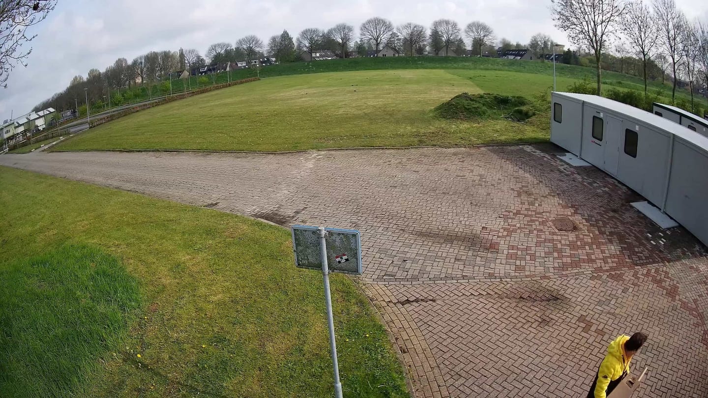 50+ Bewakingscamera Tips en Adviezen: camerabeeld overdag van een grasveld en een verhard terrein met een bord