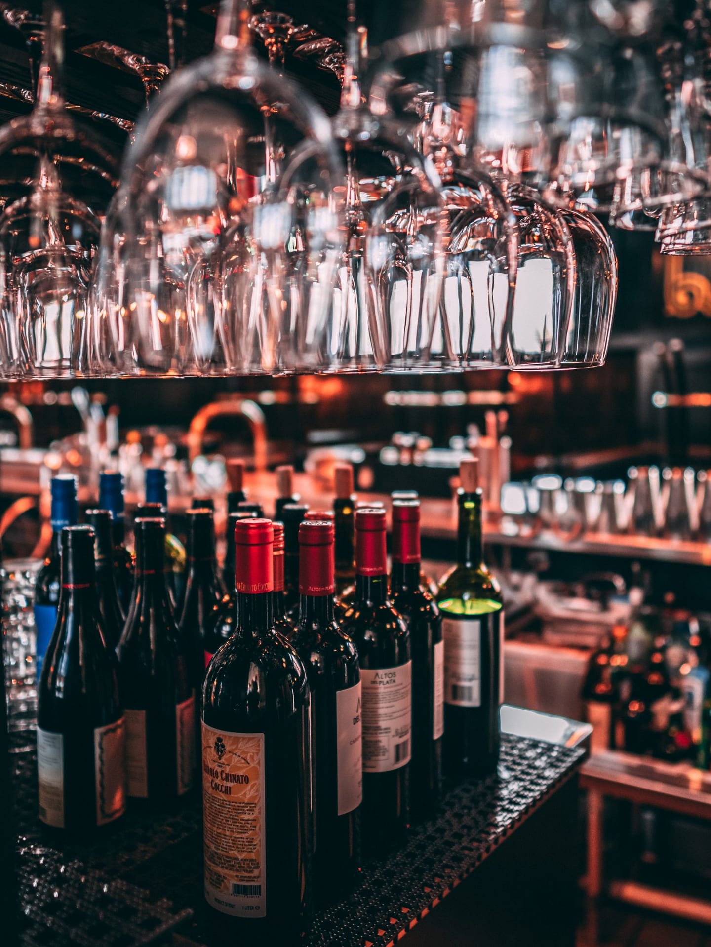 Camerabewaking horeca: hangende wijnglazen en flessen wijn achter een bar