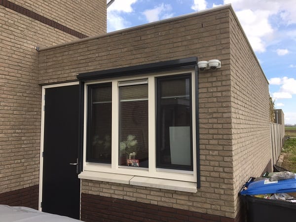 Camerabeveiliging Particulier: bakstenen woning met een zwarte voordeur en een raam
