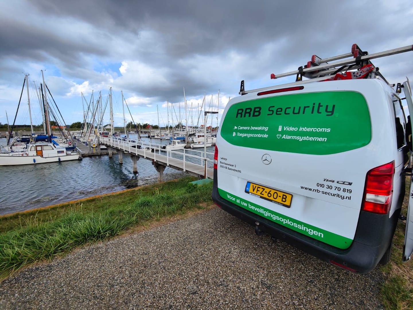 Camerabeveiliging Jachthaven: witte servicebus van RRB Security bij een jachthaven met zeilboten