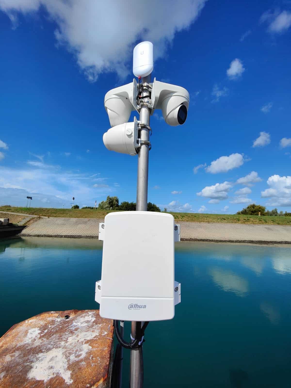 Camerabeveiliging Jachthaven: camera met twee lenzen en een kastje op een paal aan het water